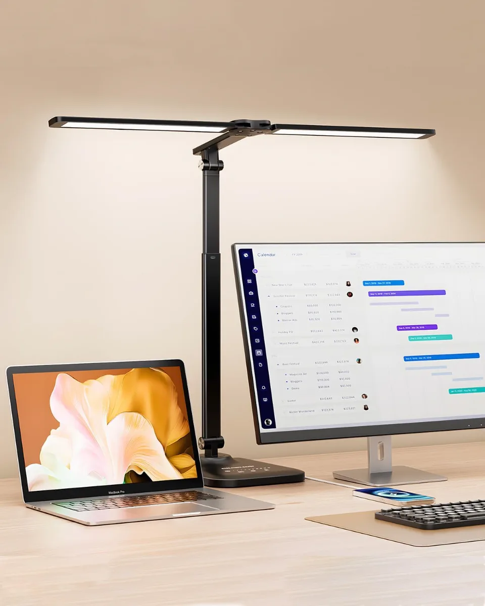 Aesthetic desk setup on a budget showing a laptop stand, cable management tray, LED desk lamp, fake eucalyptus plants, and warm white LED strip lights on a clean desk.