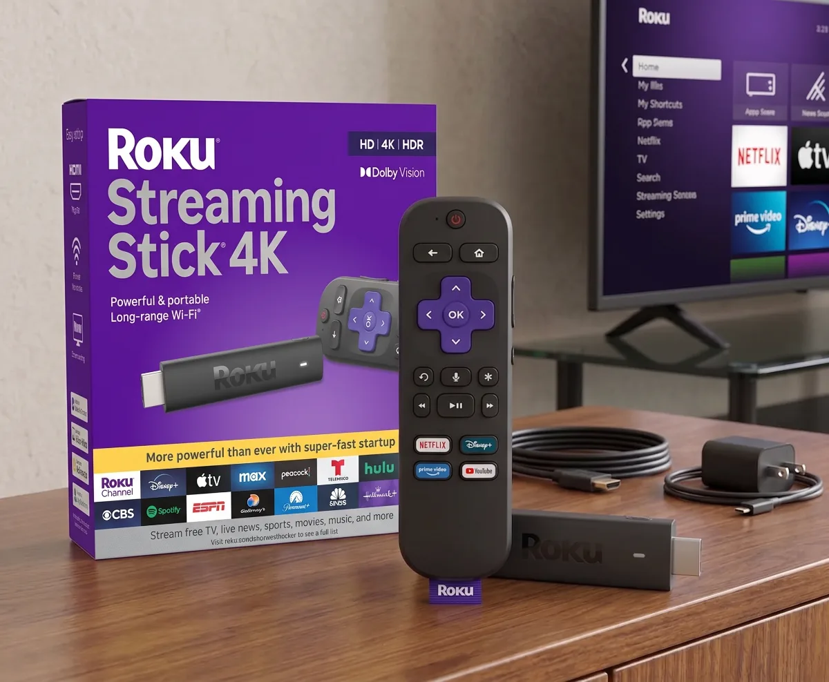 Fire TV Stick 4K Max and Roku Streaming Stick 4K side by side on a modern TV stand
